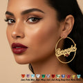 A close-up of a woman wearing a large gold hoop earring with the name 'Bernadet' cut into the front and a small red heart charm. The image includes the text 'Custom Name' and shows a row of colorful heart gem options along the bottom.