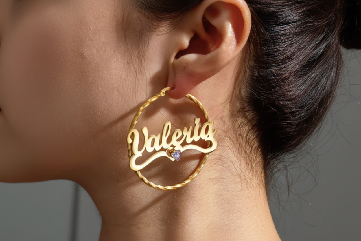 A close-up of a person's ear wearing a large gold hoop earring with the name 'Valeria' in cursive script and a small purple gemstone accent.