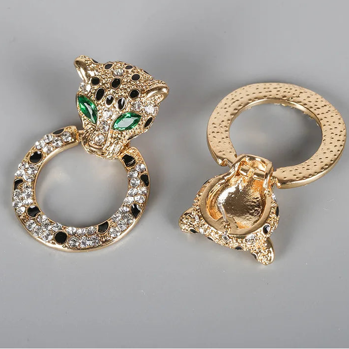 Two gold-toned leopard ring holders with rhinestone and green stone detailing, shown on a light gray background with a 'lennik' brand logo in the top left corner.