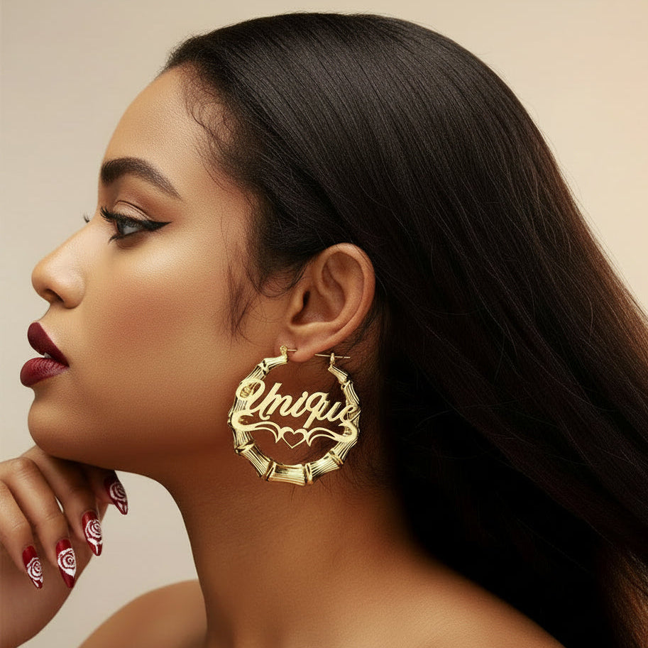A close-up of a model's ear wearing a large gold hoop earring with a bamboo-inspired textured border and the word 'Unique' in script across the front.