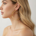 Gold hoop earring worn by a person with a neutral background